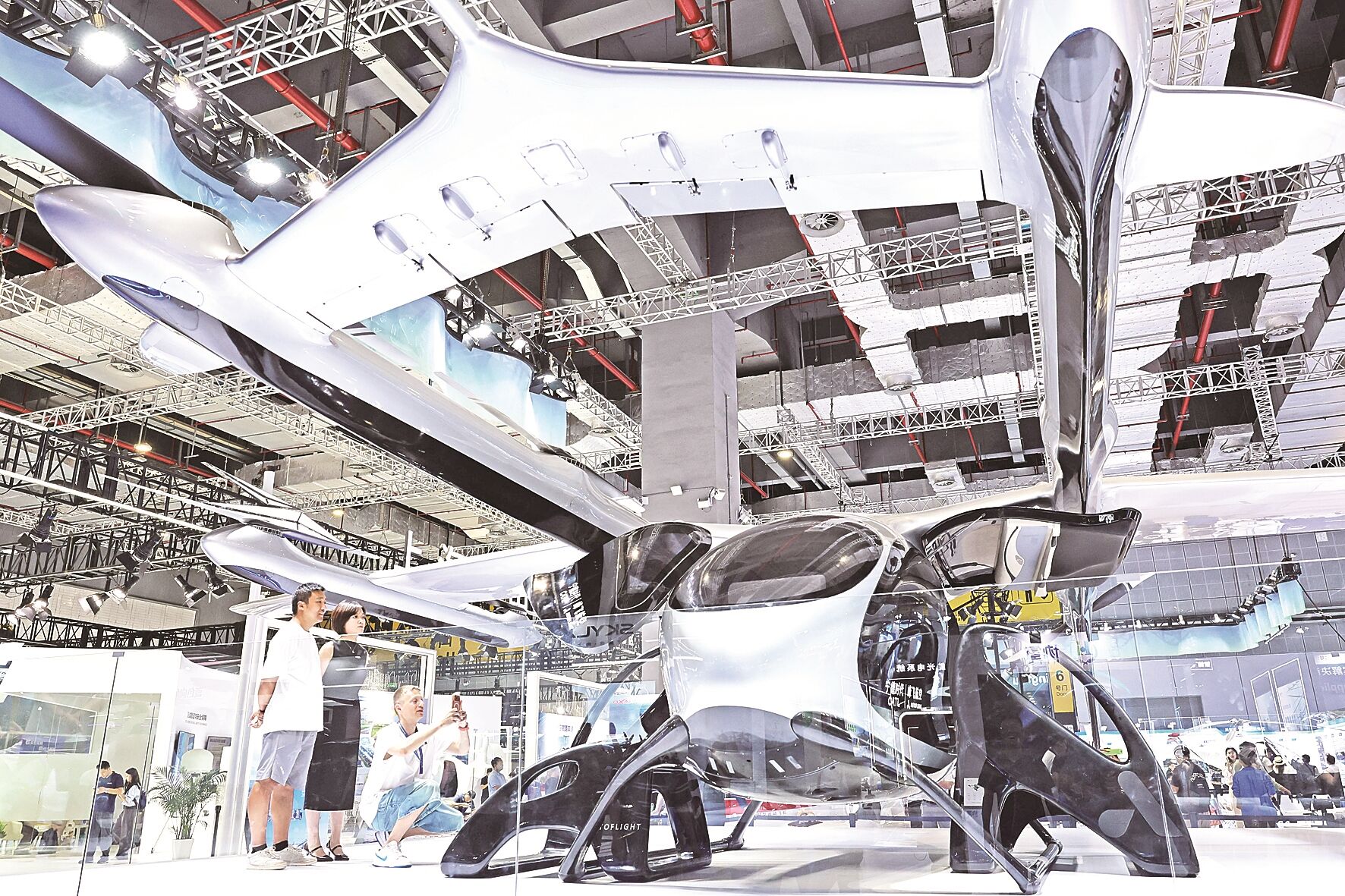 参观者在峰飞航空展台一架V2000EM盛世龙电动垂直起降飞行器旁参观。