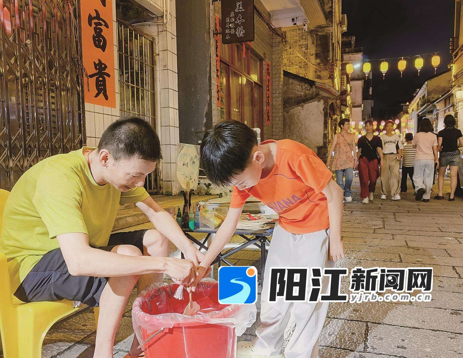 摊主手把手教小朋友体验制作漆扇。
