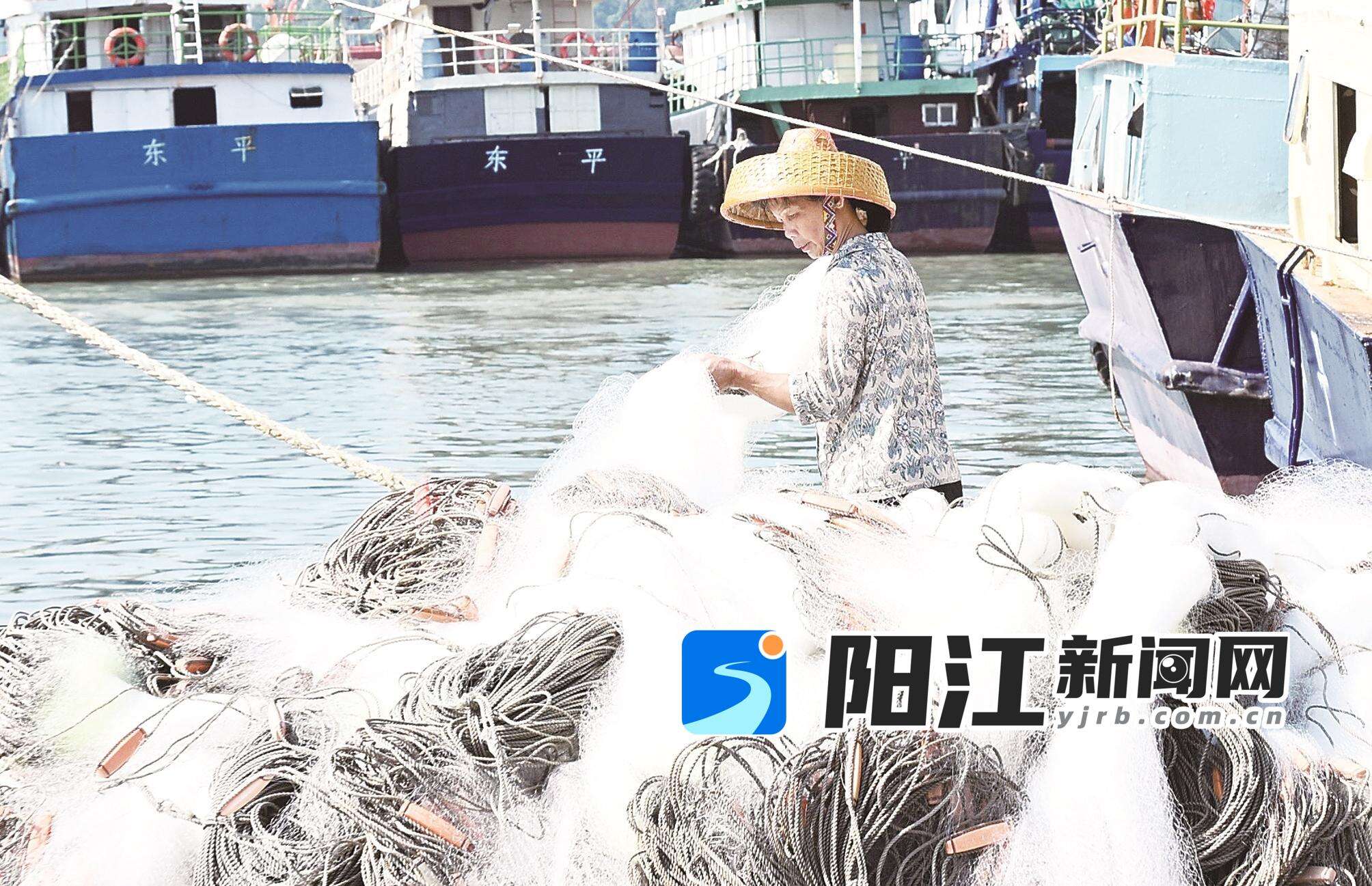 东平渔港码头上,渔民顶着烈日整理修补渔网。陈建华 摄