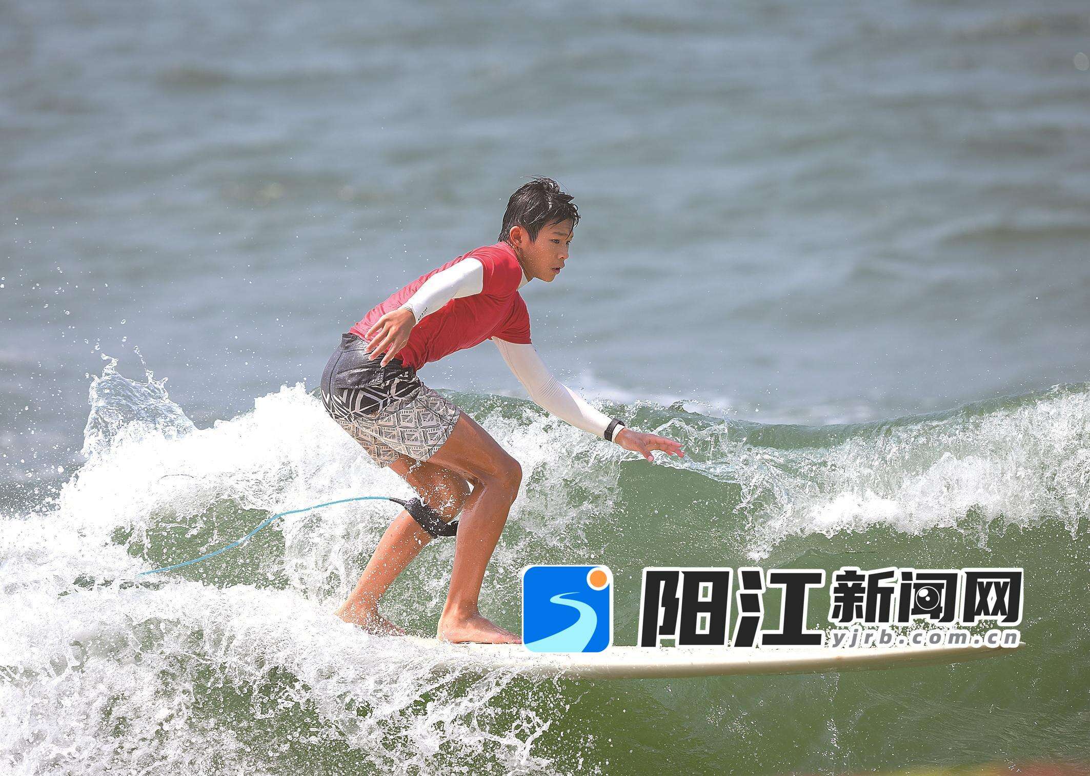 少年运动员脚踏冲浪板,在海面上乘浪飞驰。梁文栋 摄