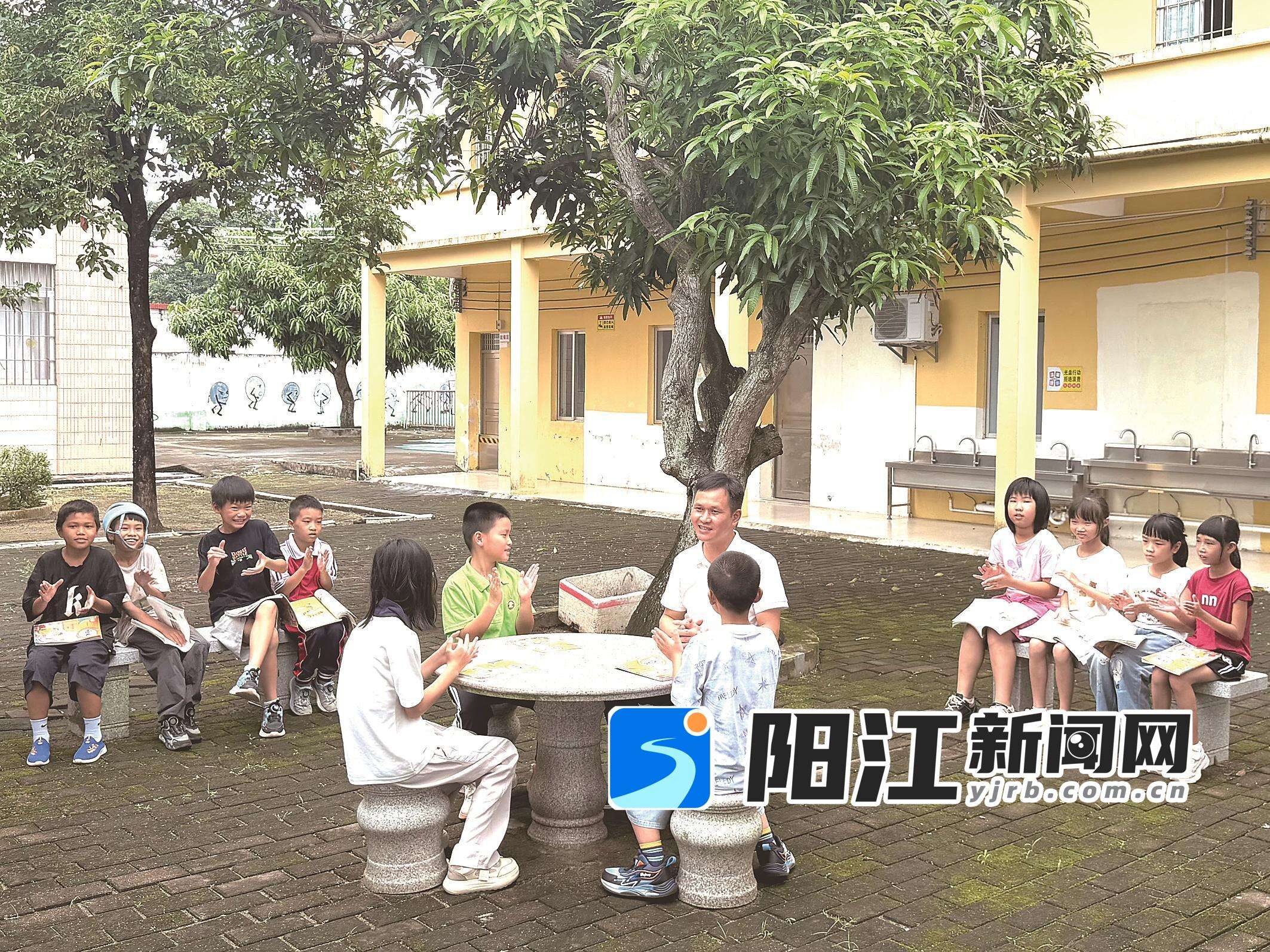 良洞村“文艺村长”在树荫下给爱好阅读和写作的小学生分享读书的方法与心得。 曾宪雯 摄